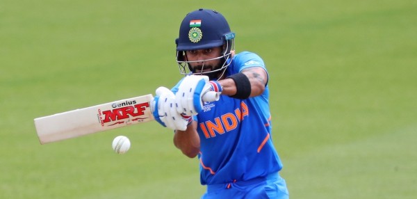 Virat Kohli, wearing a blue shirt with 'India' written across the middle in orange letters, plays a cut shot in a T20 match